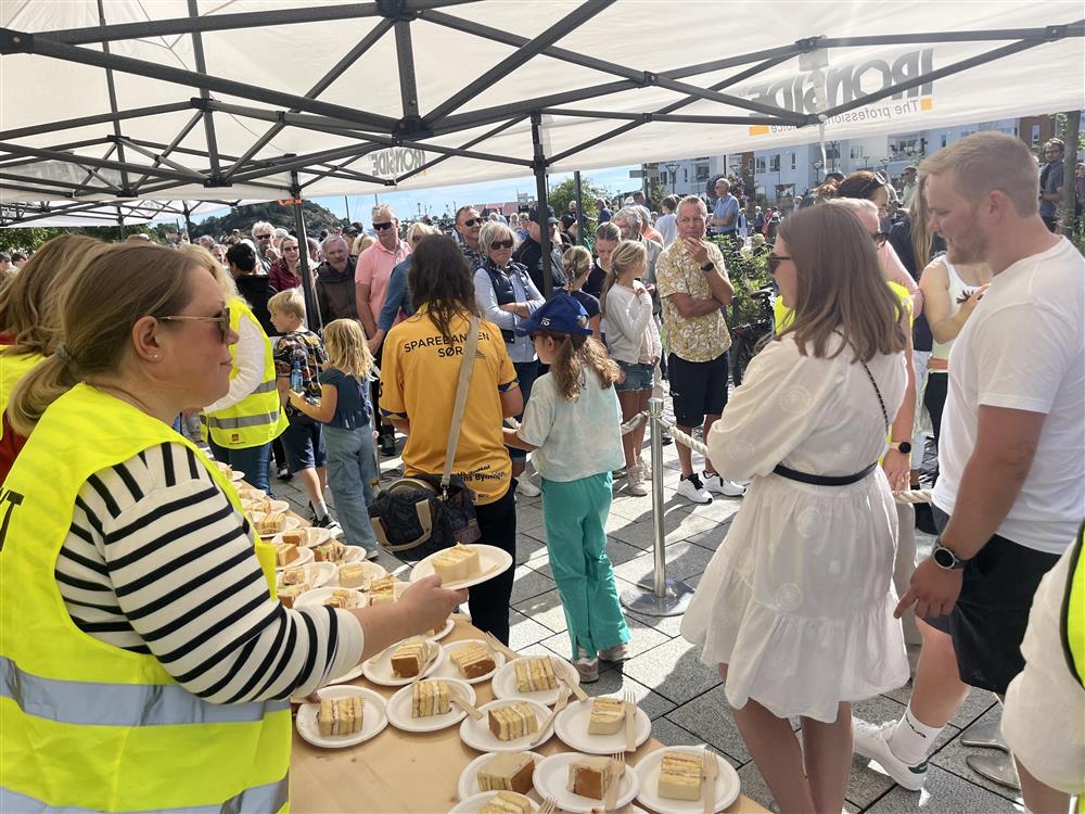 Folk står i kø og får gratis kake - Klikk for stort bilde