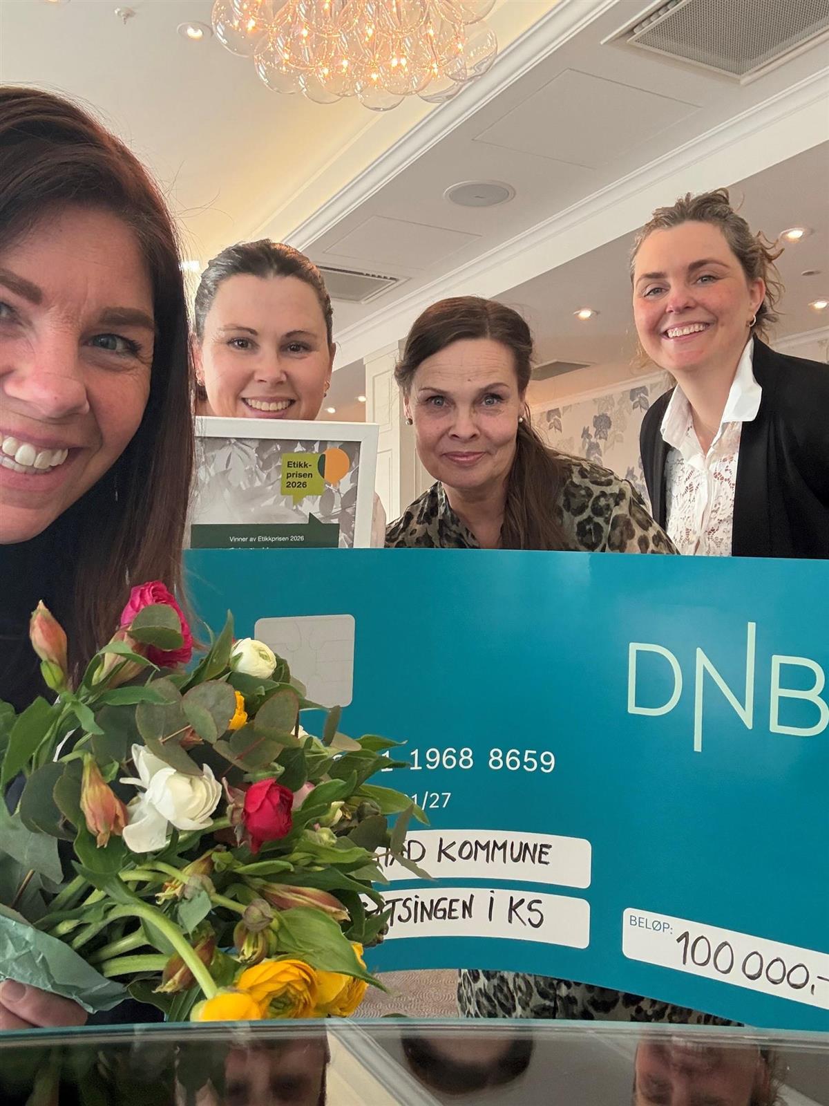 Fire glade damer smiler bak en sjekk og fargerike blomster - Klikk for stort bilde